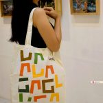 Dokumentasi kehadiran tote bag blacu custom NOM Souvenir di Ubud Art Ground, menampilkan pengunjung pameran internasional menenteng tas dengan desain logo full color yang estetik